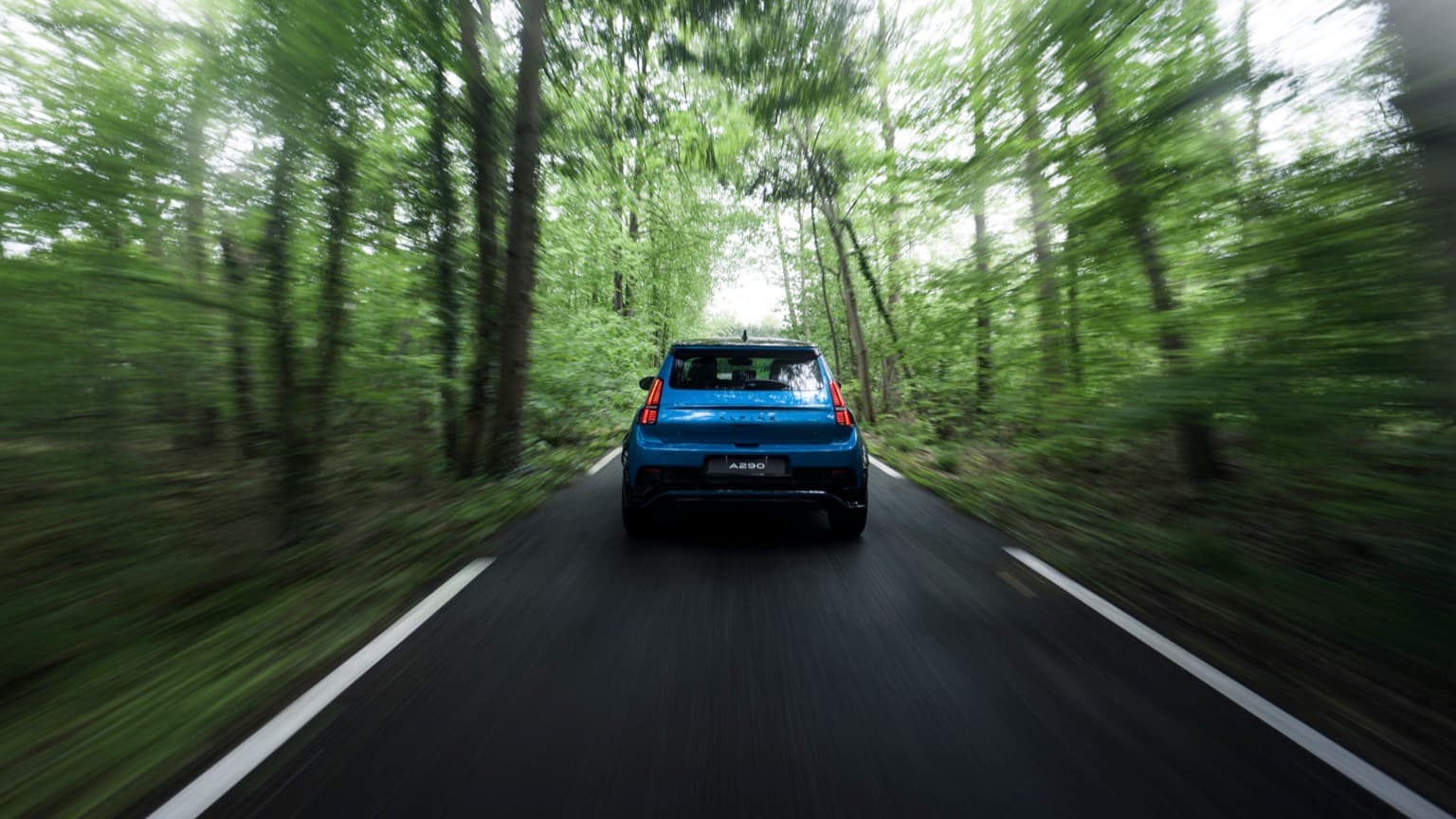 une voiture roulant sur une route à travers les arbres