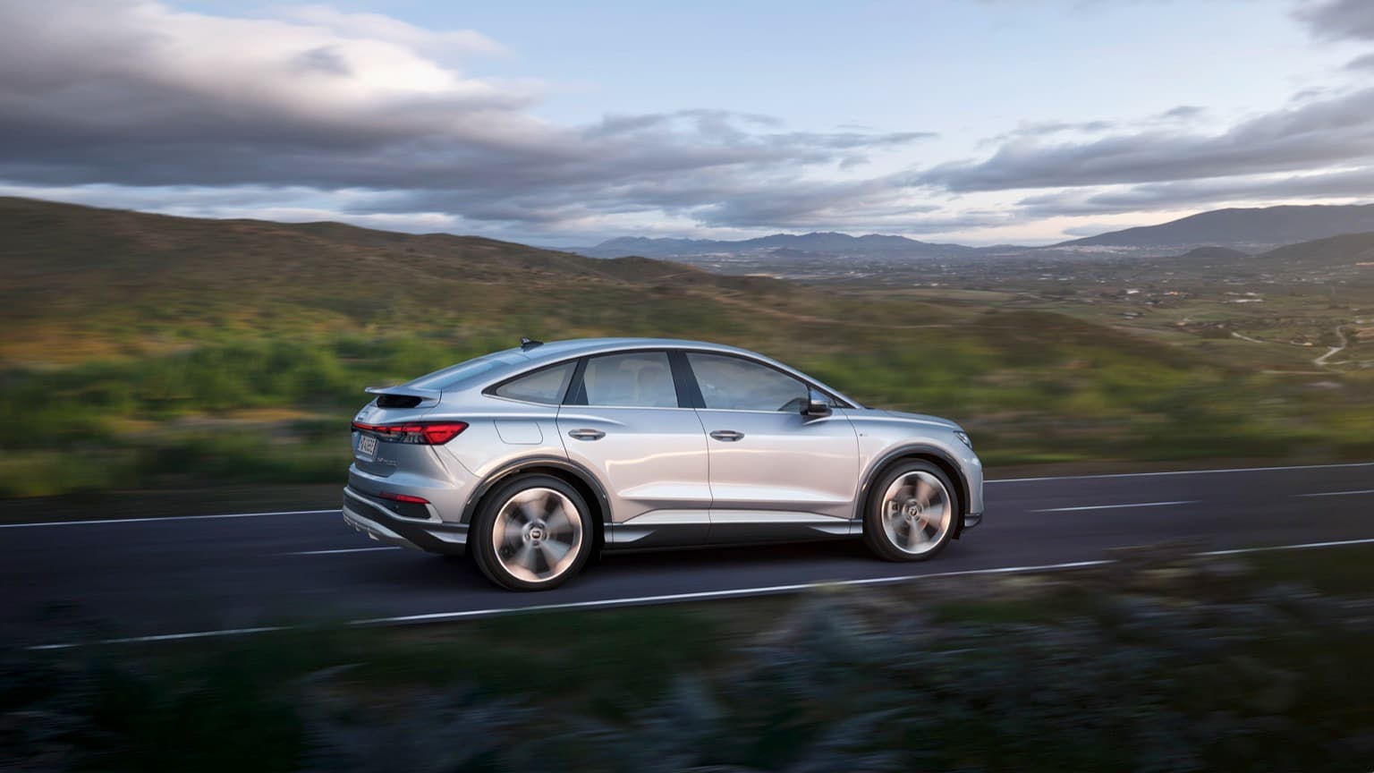 a silver car driving on a road