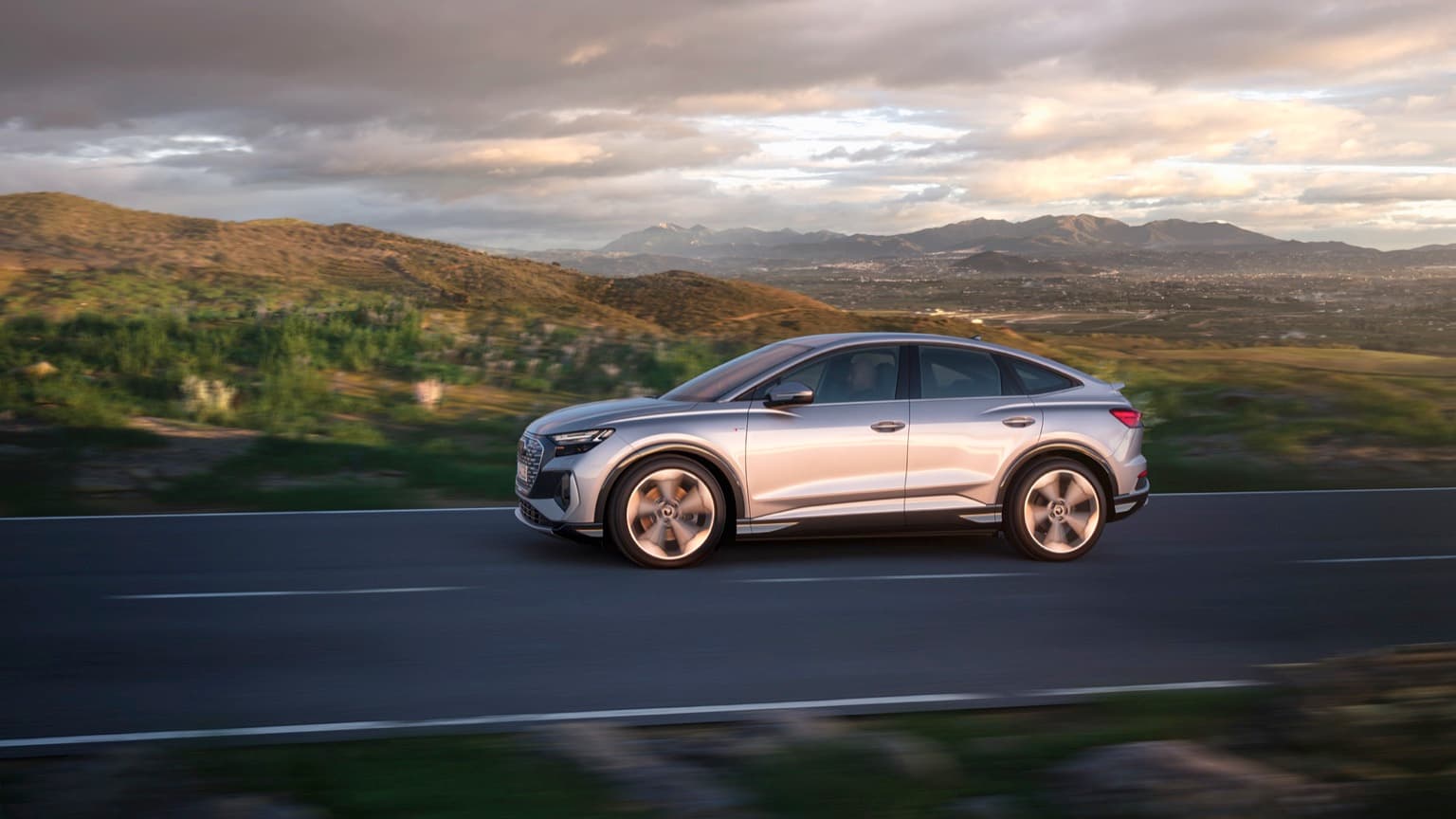 a silver car driving on a road