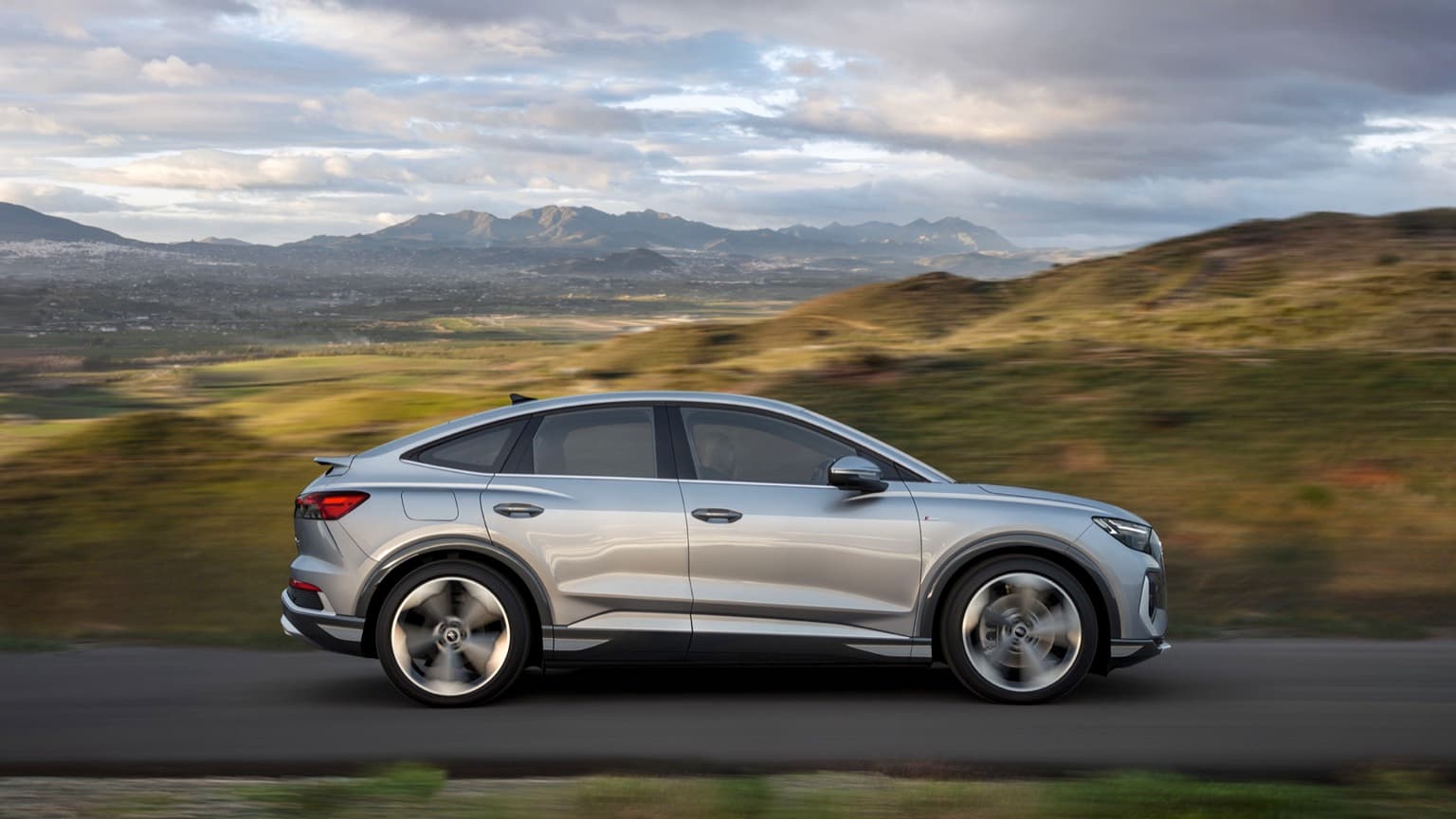 a silver car driving on a road