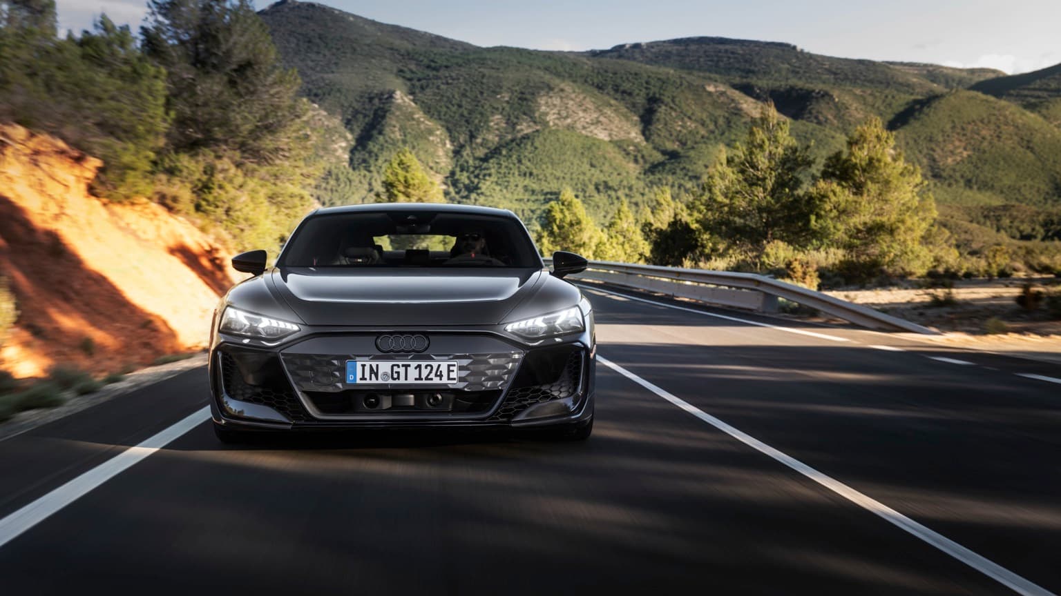 a black car driving on a road with mountains in the background