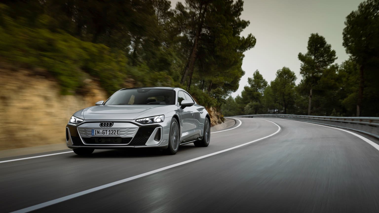 a silver car driving on a curvy road