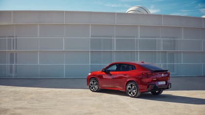 une voiture rouge garée devant un mur blanc