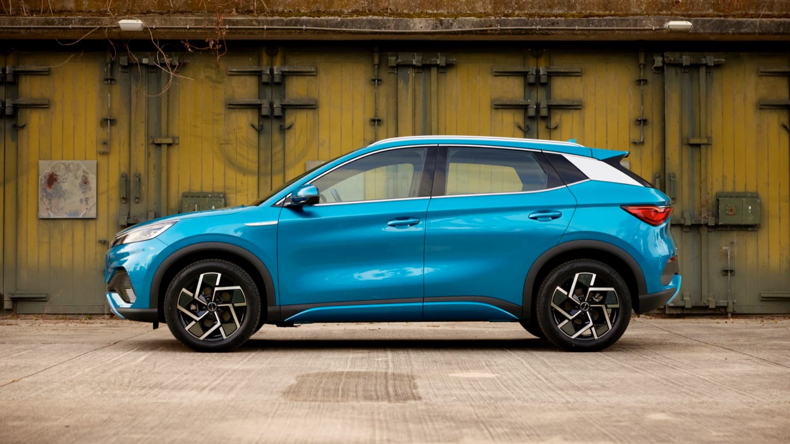 une voiture bleue garée devant une porte jaune