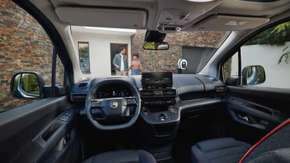 à l'intérieur d'une voiture avec un volant et un homme et une femme debout à l'arrière-plan