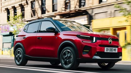 une voiture rouge roulant dans une rue