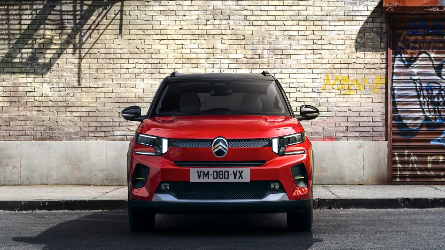 a red car parked in front of a brick wall