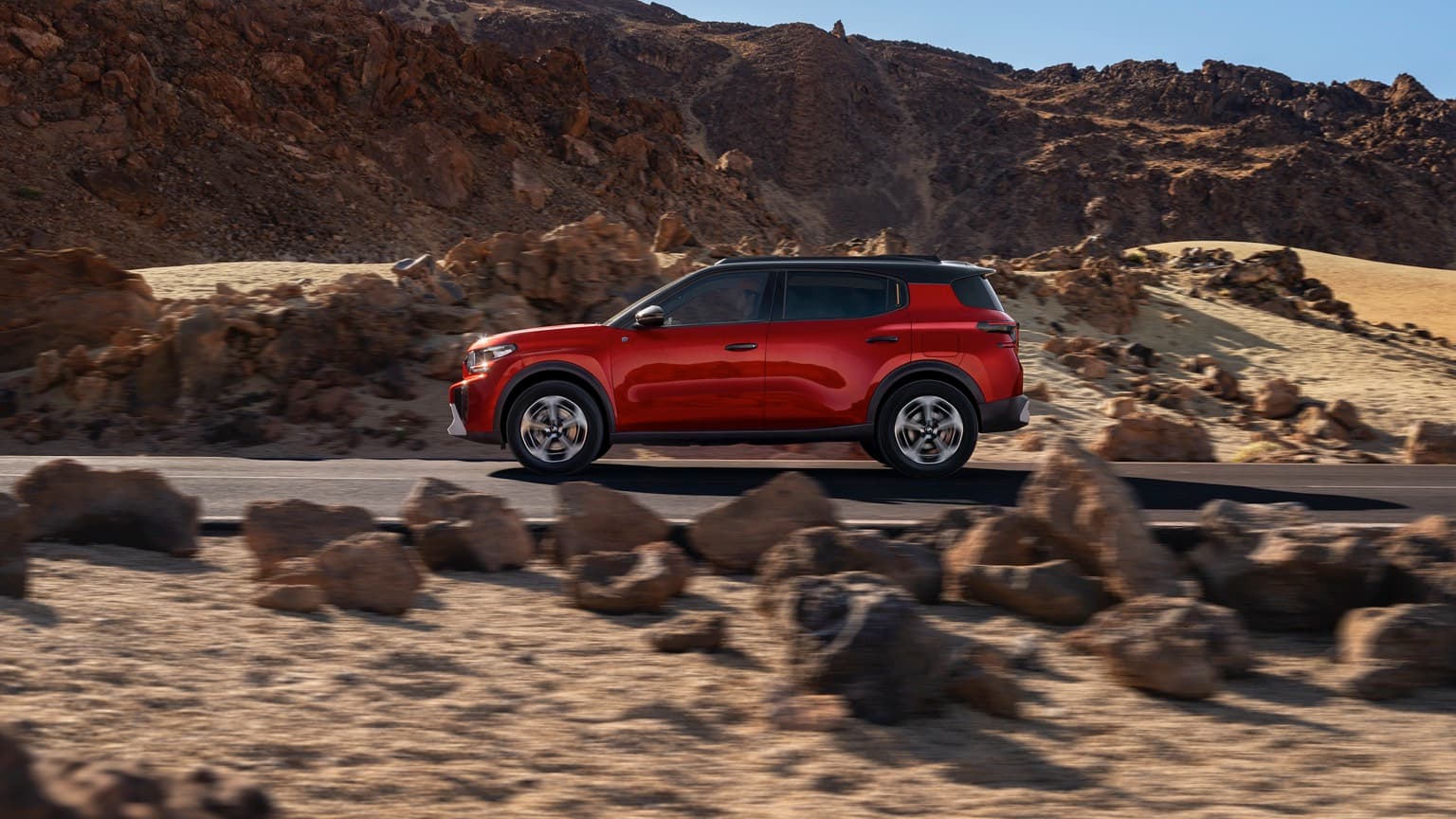 a red car driving on a desert road
