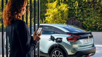 une femme tenant un téléphone à côté d'une voiture