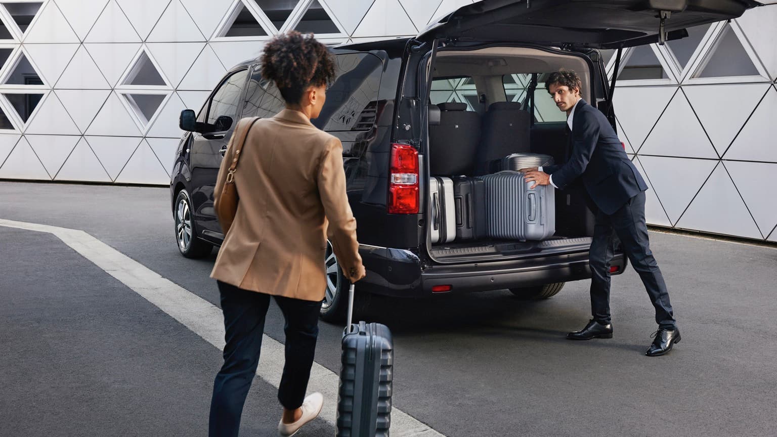 a man and woman with luggage in the back of a van