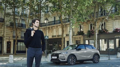 a man standing on a street with a car parked on the side