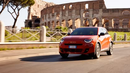 voiture rouge roulant sur une route avec un bâtiment en pierre à l'arrière-plan