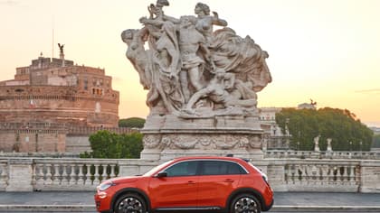 une voiture rouge garée sur un pont avec une statue de personnes