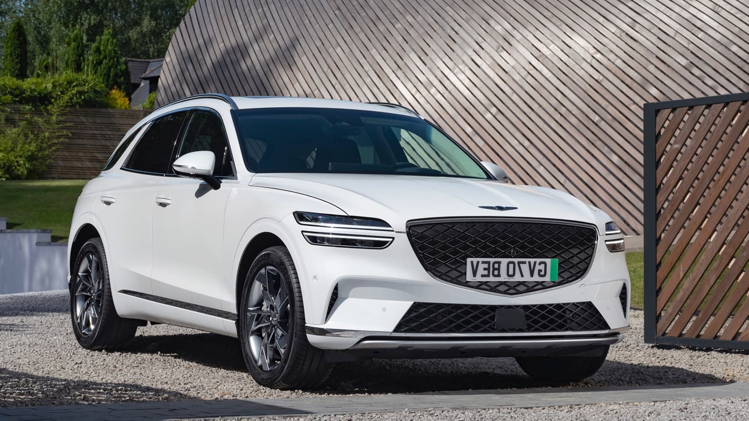 a white car parked in front of a wood wall