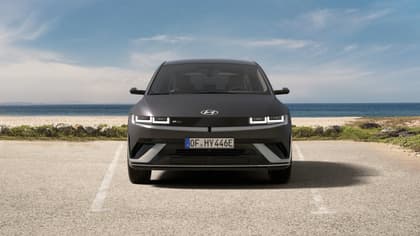 une voiture noire garée sur une route avec de l'eau en arrière-plan