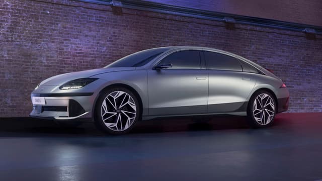 a silver car parked in front of a brick wall