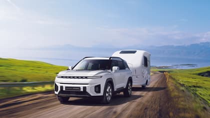 a white car with a trailer on a road
