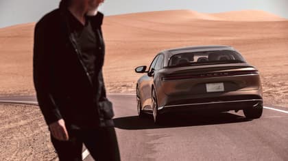 un homme passant devant une voiture noire