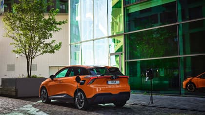 an orange car parked in front of a glass building
