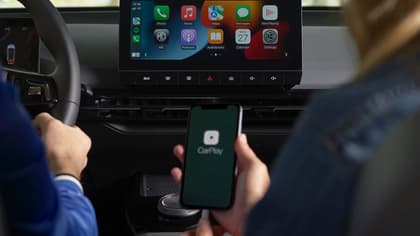 a person holding a phone in front of a car
