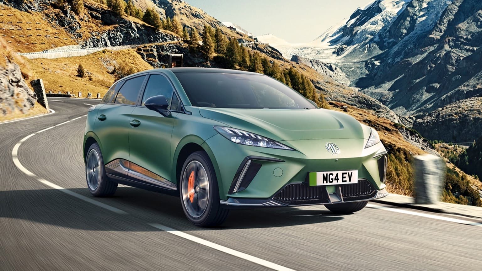 a green car driving on a road with mountains in the background