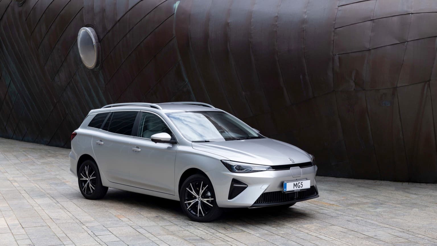 a silver car parked in front of a large metal ship