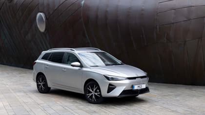 a silver car parked in front of a large metal ship