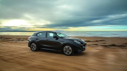 une voiture noire roulant sur une plage de sable