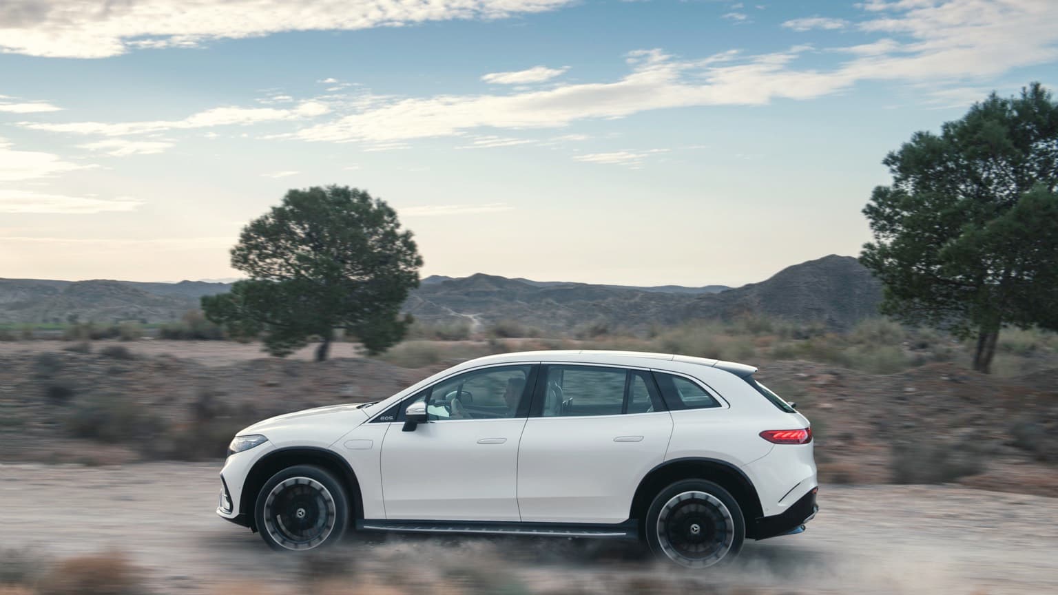 a white car driving on a dirt road