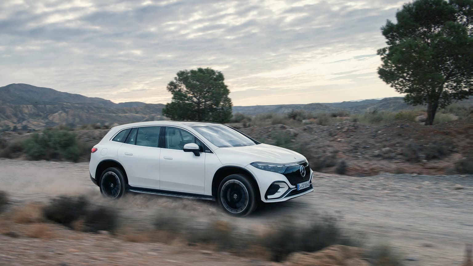 a white car driving on a dirt road