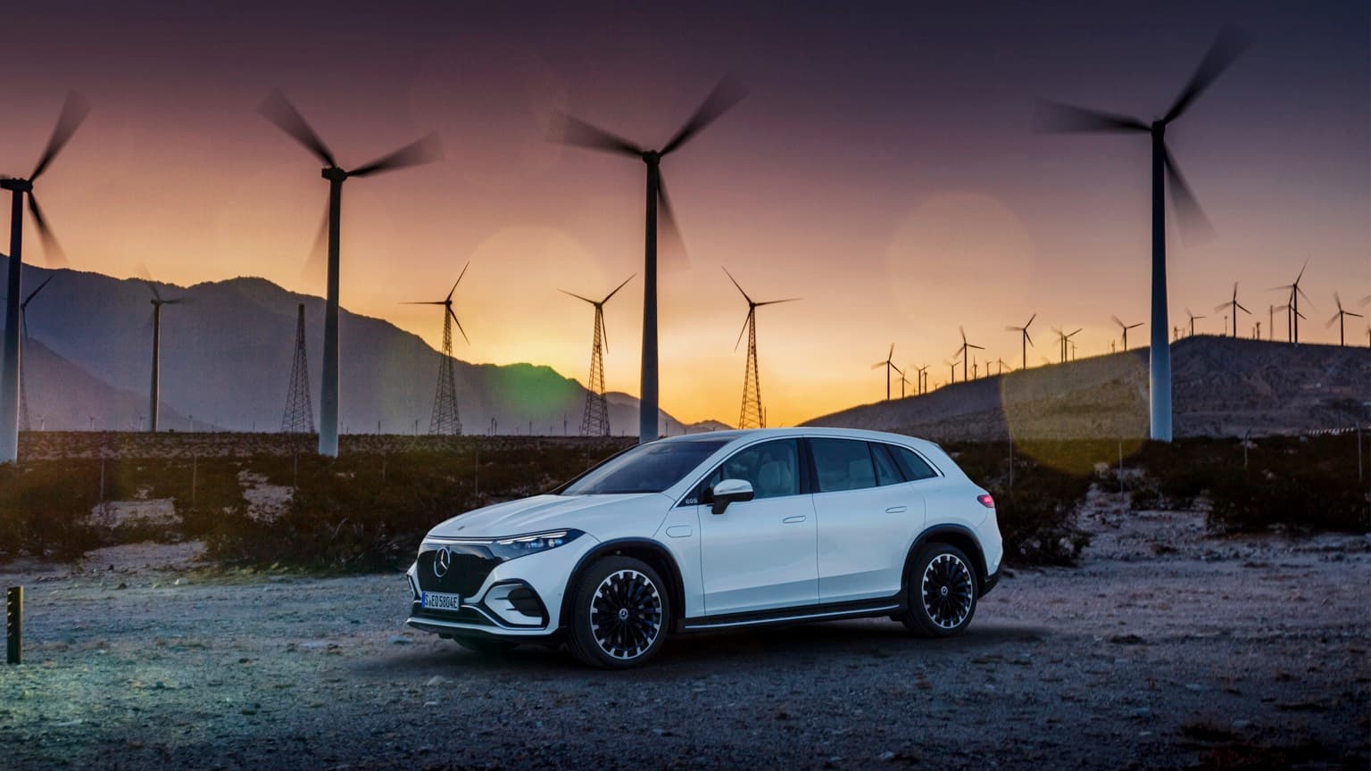 a car parked on a dirt road with wind turbines in the background