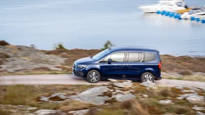 une voiture bleue roulant sur une route près d'une étendue d'eau