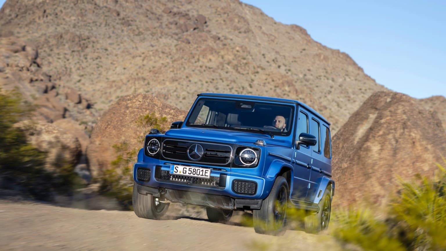 une voiture bleue roulant sur un chemin de terre