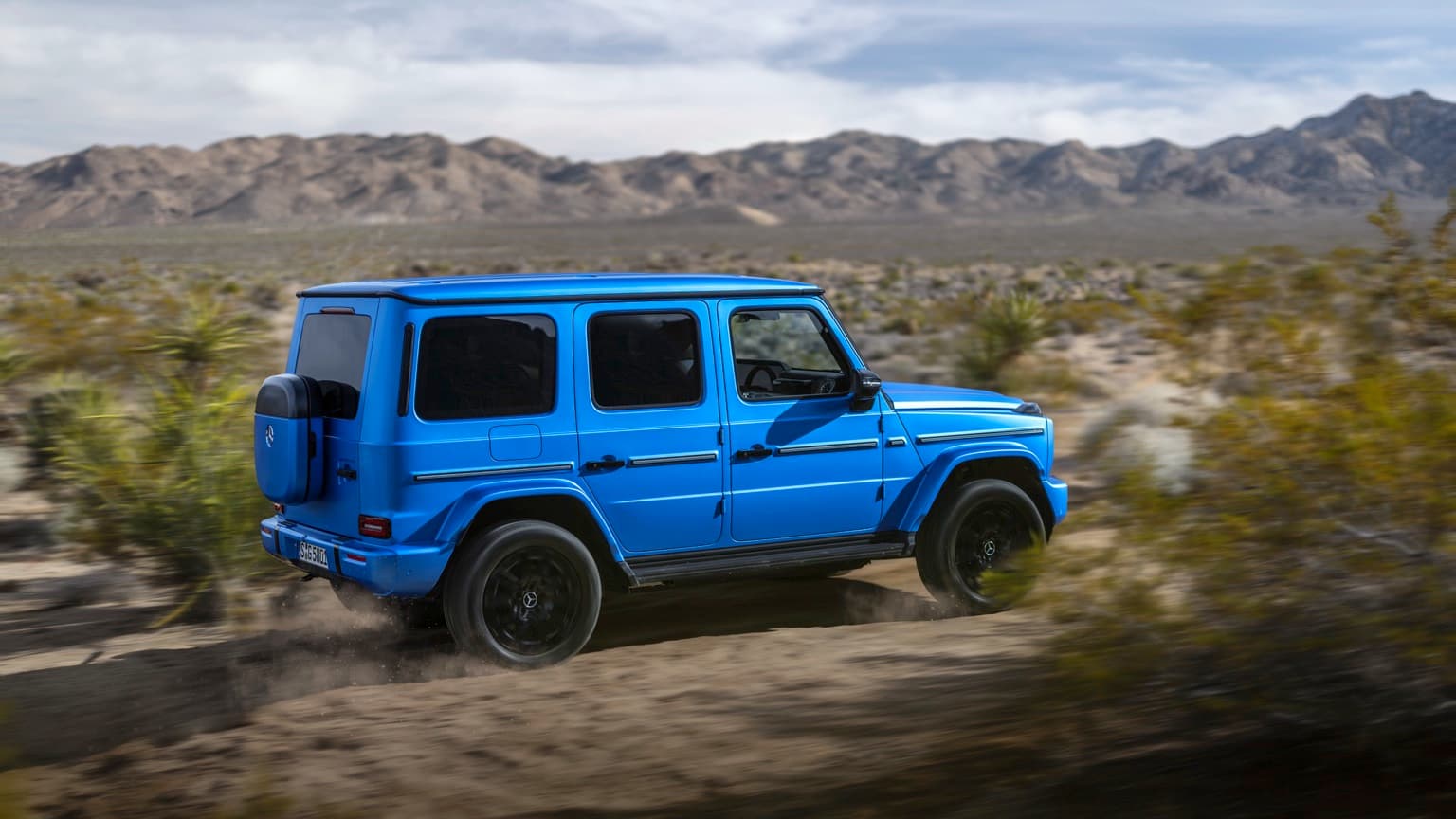 une jeep bleue roulant sur un chemin de terre
