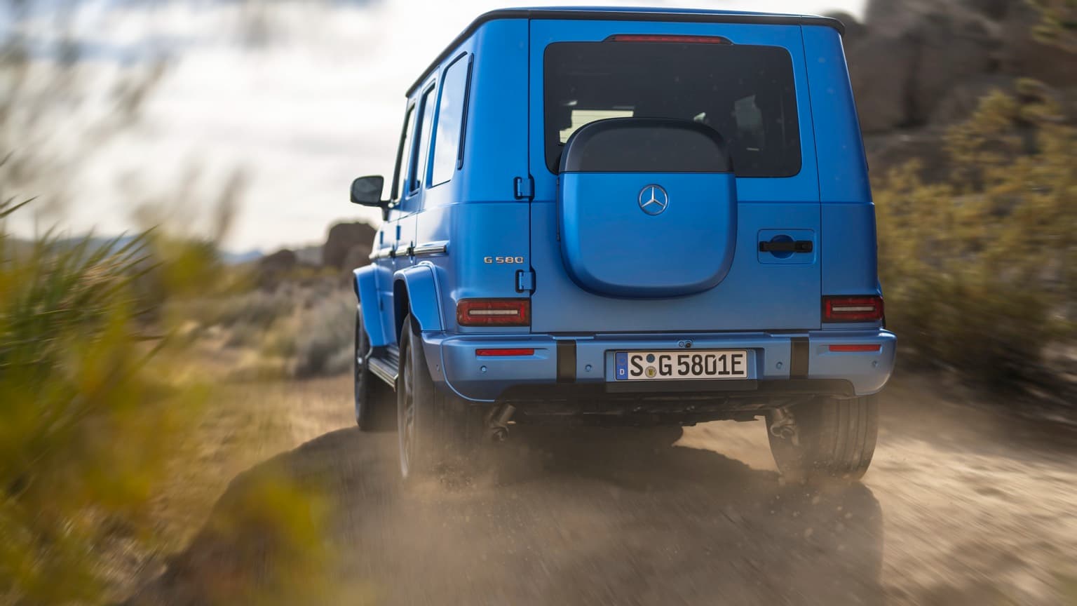 une voiture bleue roulant sur un chemin de terre