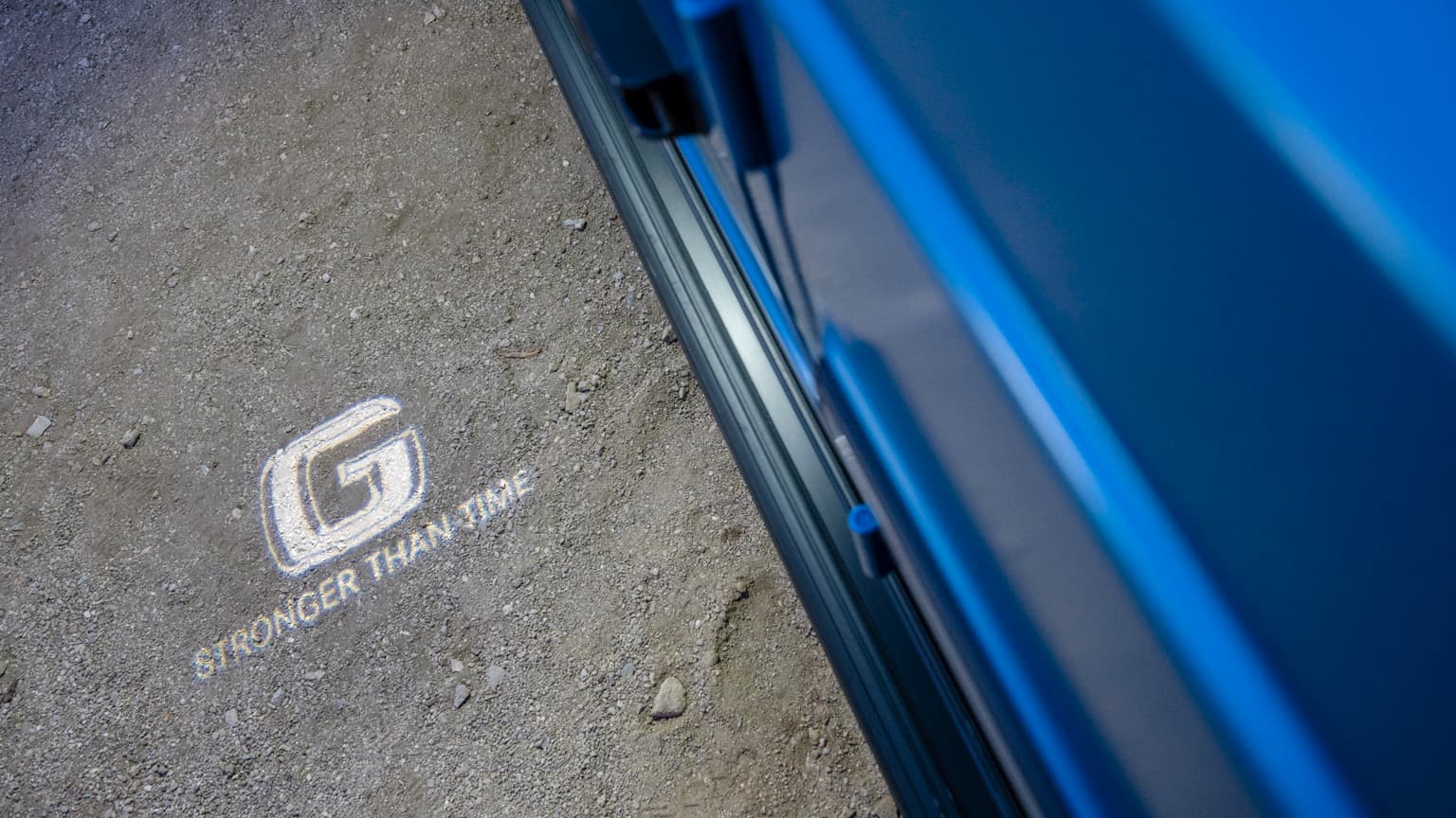 une voiture bleue avec un logo blanc sur le sol