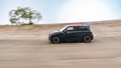 a black car with red roof driving on a dirt road
