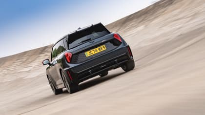 a black car driving on a sandy road