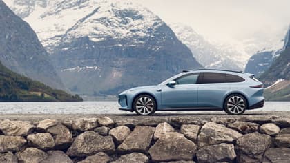 une voiture garée sur une route près de l'eau et des montagnes