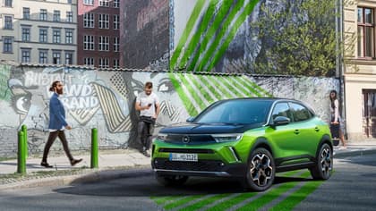 un homme debout sur un trottoir à côté d'une voiture verte