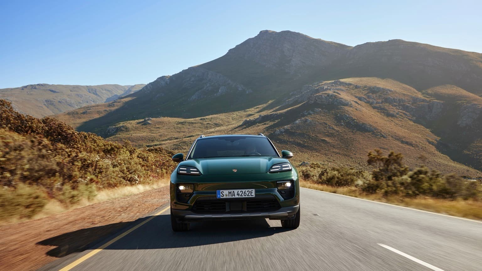a car driving on a road with mountains in the background