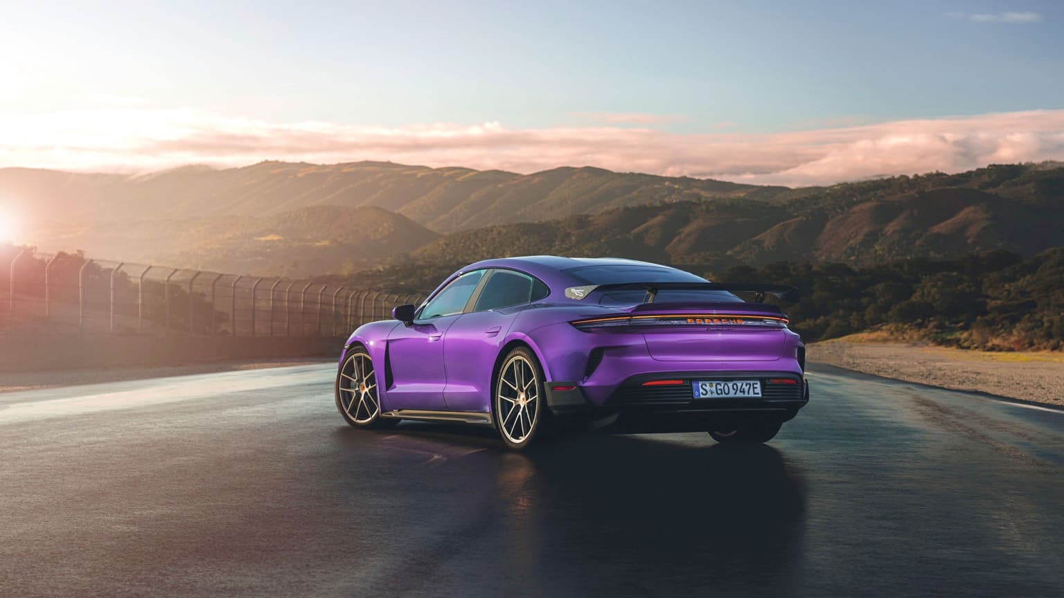 a purple sports car on a road with mountains in the background