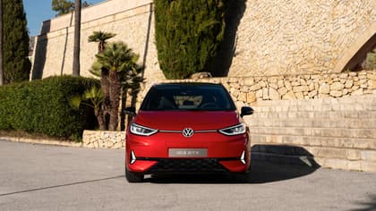 une voiture rouge garée devant un mur de pierre