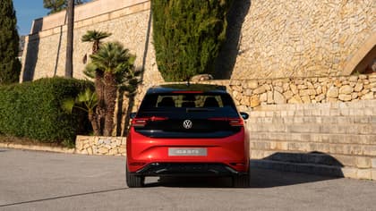 une voiture rouge garée devant un mur de pierre