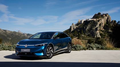 une voiture bleue garée sur du béton avec une colline en arrière-plan