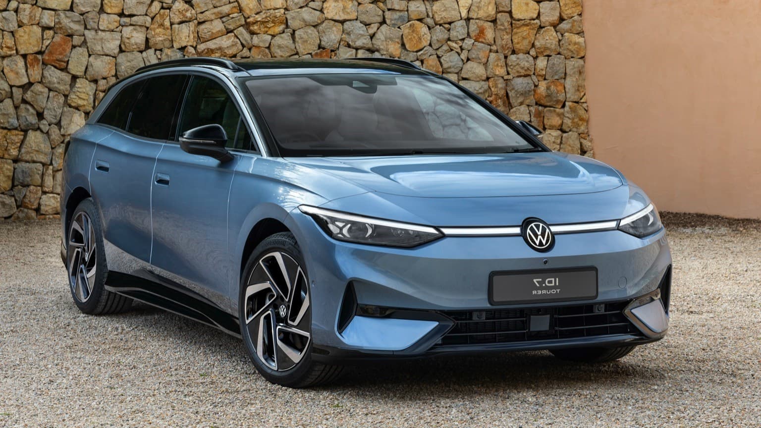 a blue car parked in front of a stone wall