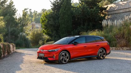 une voiture rouge garée sur du gravier près d'arbres