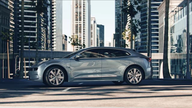 a silver car parked on a street with tall buildings in the background