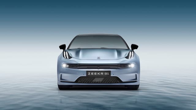 a blue sports car with its headlights on