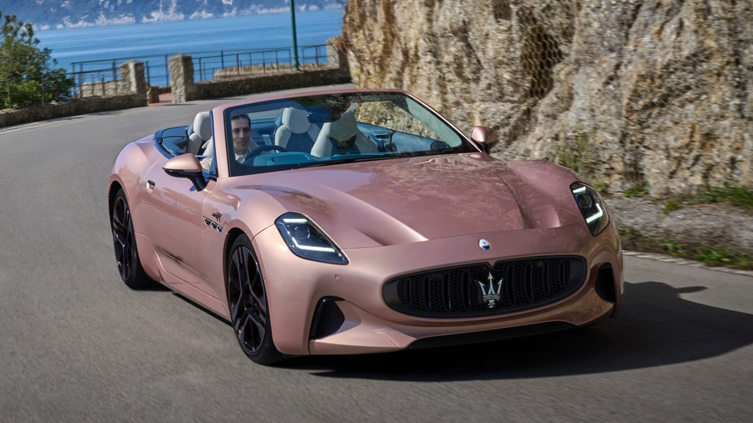 a man driving a pink convertible car